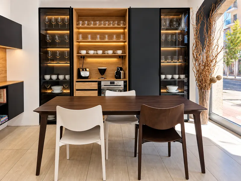 Vitrinas negras y armario de madera iluminado junto a la mesa de comedor