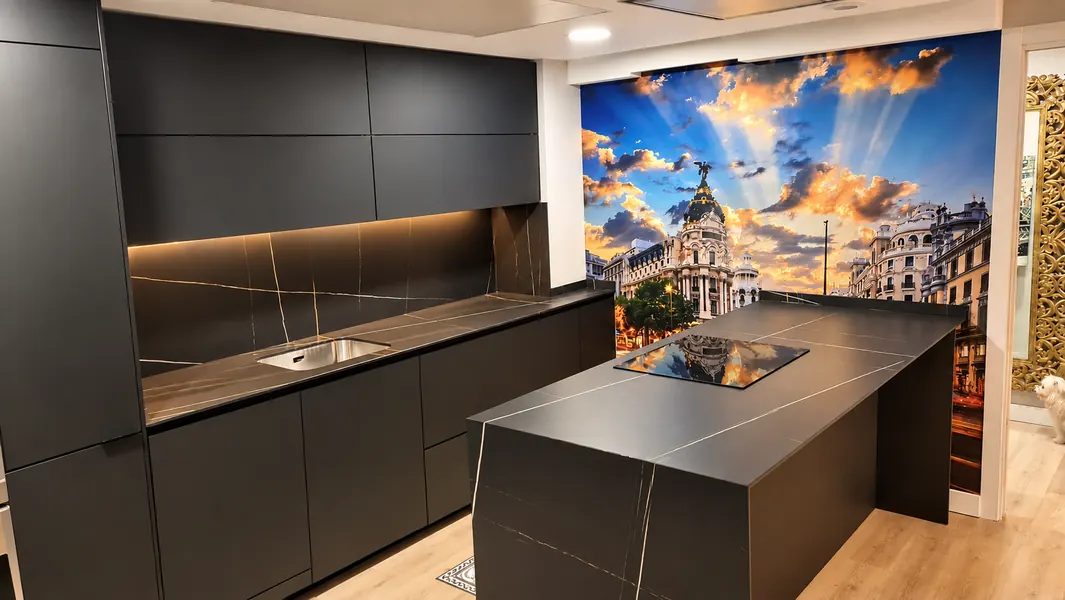Cocina negra con isla y mural fotográfico de Madrid en la pared