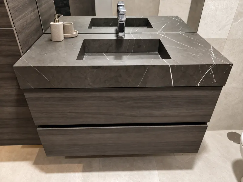Lavabo integrado de piedra gris veteada sobre mueble de madera