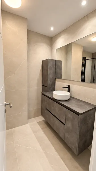 Baño con mueble gris, lavabo sobre encimera y espejo de pared