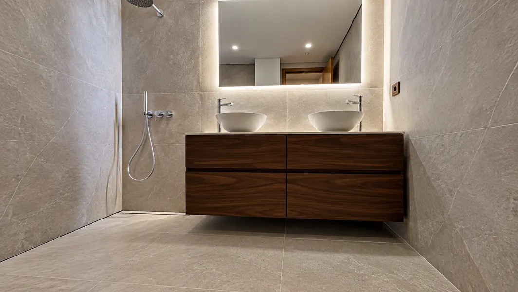 Baño con ducha a ras de suelo, doble lavabo y mueble de nogal suspendido