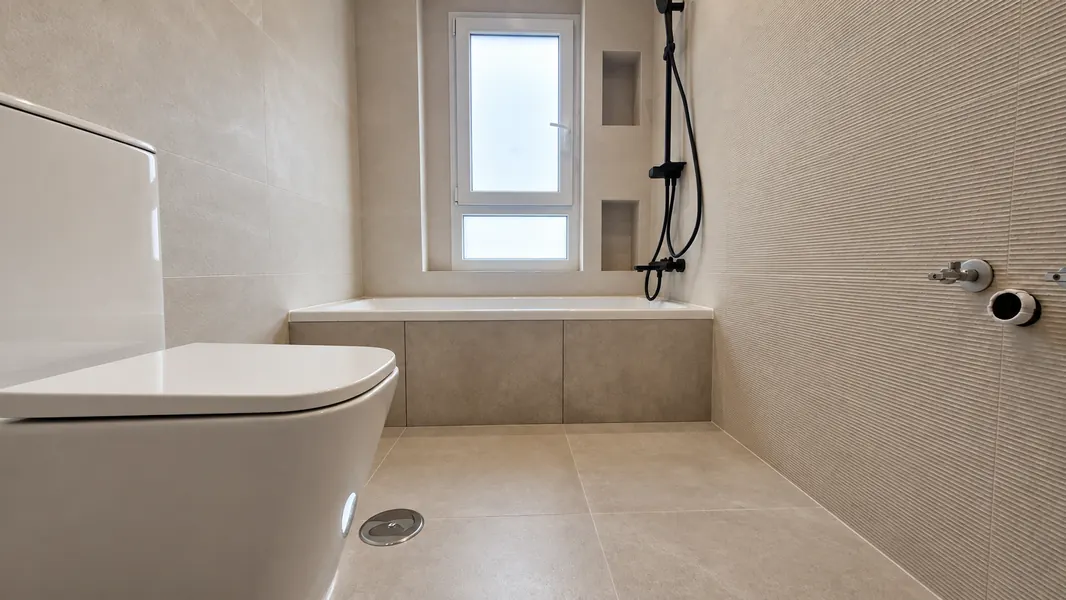 Baño con bañera bajo la ventana y grifería negra