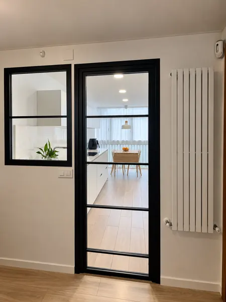 Puerta de cristal con perfilería negra y ventana interior hacia el salón