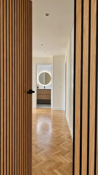 Pasillo con parquet en espiga entre listones de madera, hasta el baño